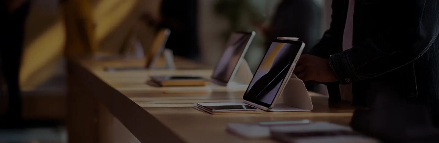 Tablets on display in a store, person reaching for one.